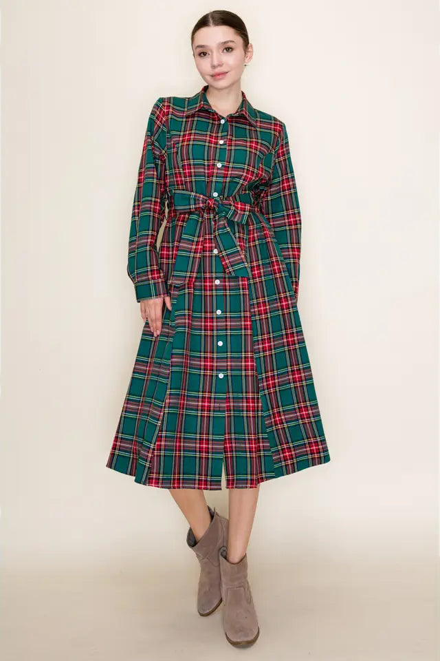 Woman wearing a green and red plaid dress with a belt on a beige background
