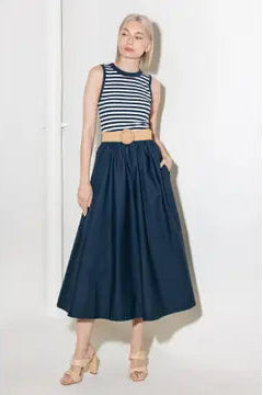 Woman wearing a striped top and long navy skirt on a white background