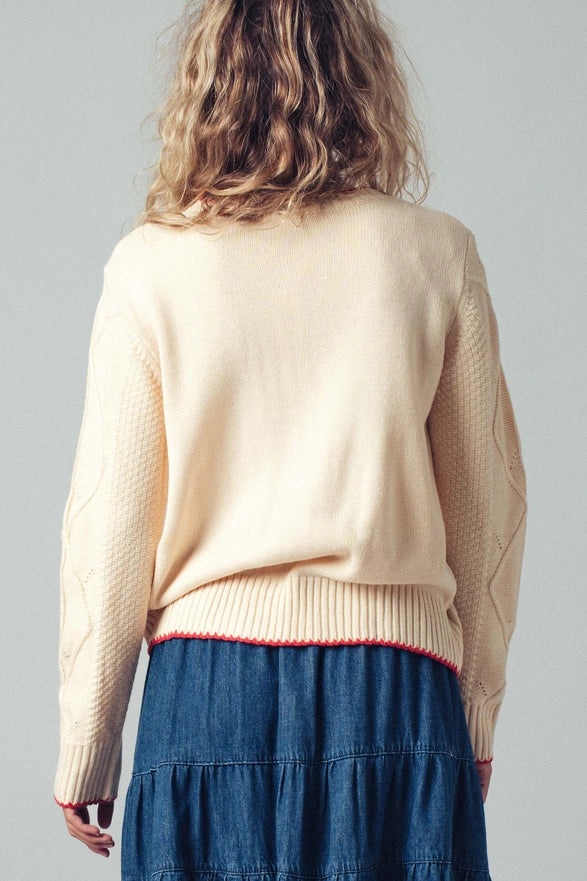 Person wearing a beige sweater and blue skirt on a gray background