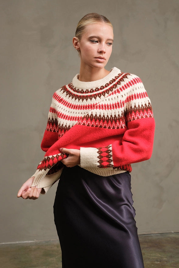 Woman wearing a red and white patterned sweater against a plain background
