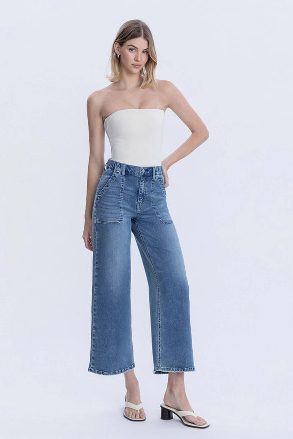 Woman wearing a strapless top and wide-leg jeans on a white background
