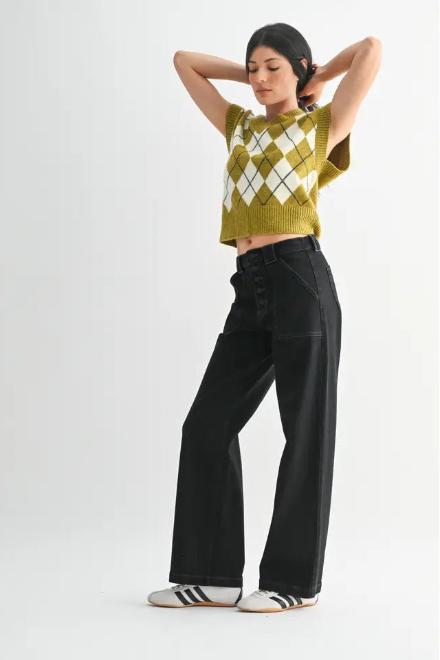 Woman wearing a green argyle sweater and black pants on a white background