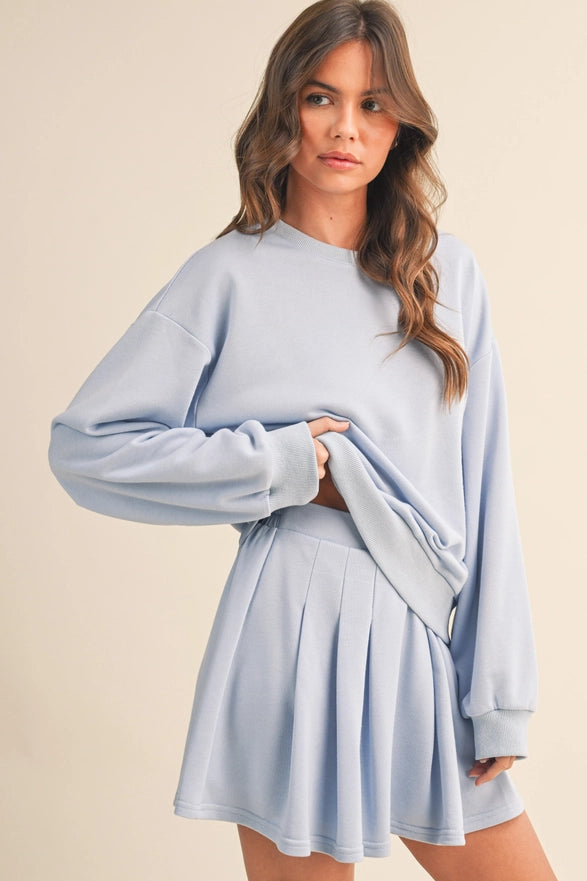 Woman wearing a light blue sweater and skirt set on a beige background