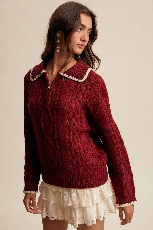 Woman wearing a red sweater with white trim against a beige background
