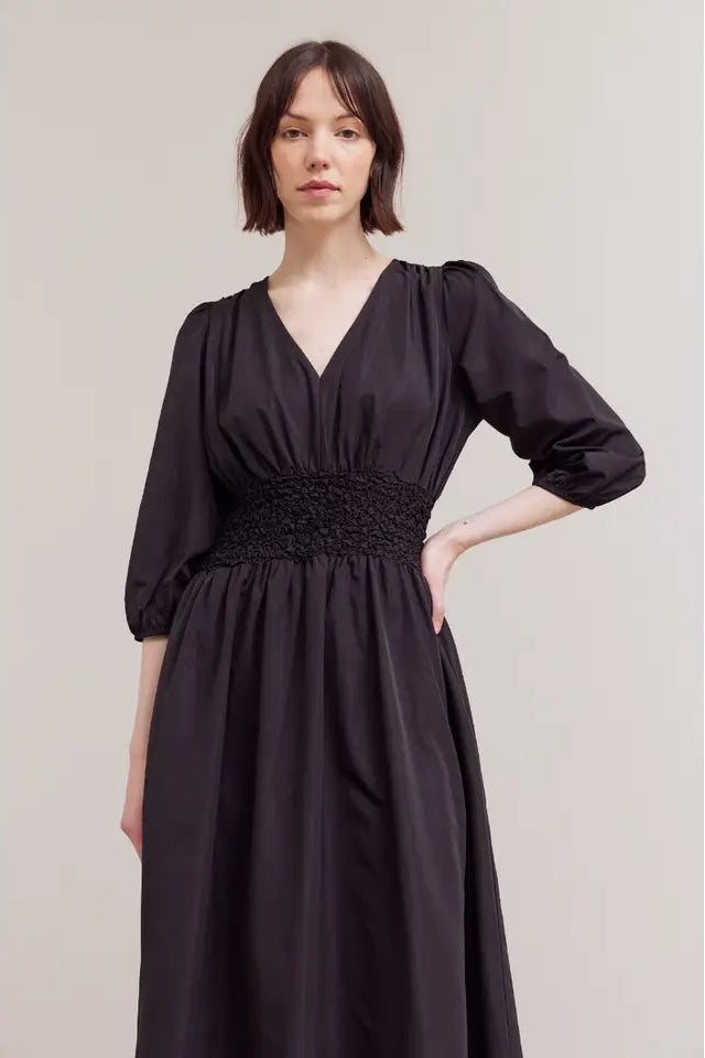 Woman wearing a black dress against a plain background