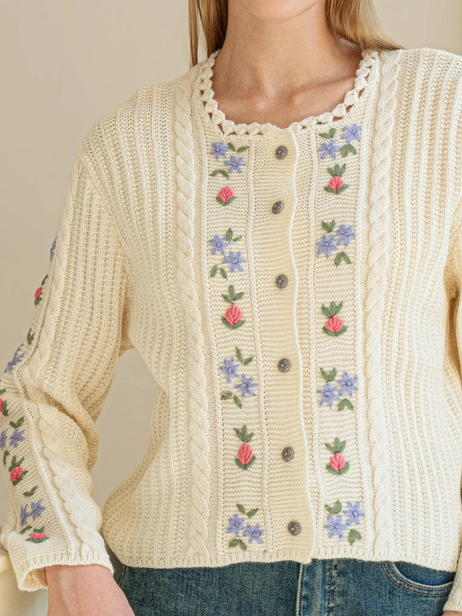 Cream-colored knitted cardigan with floral embroidery on a neutral background