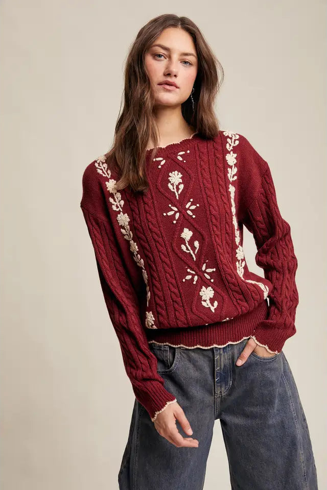 Woman wearing a red sweater with white floral patterns against a beige background