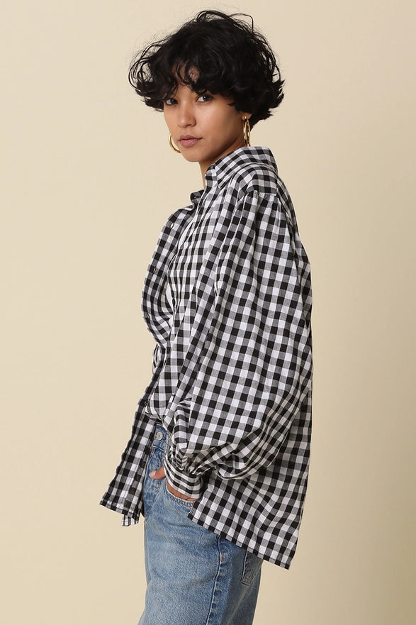 Woman wearing a black and white checkered shirt with blue jeans on a beige background
