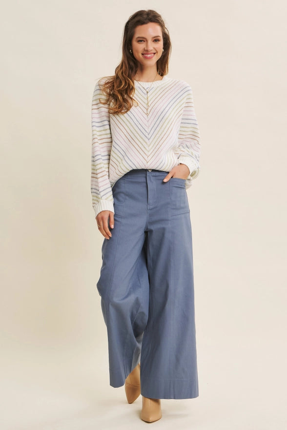 Woman wearing a striped sweater and wide-leg jeans on a beige background