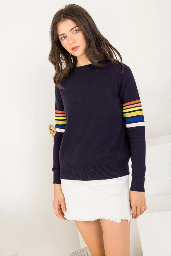 Woman wearing a navy sweater with colorful sleeves against a white background