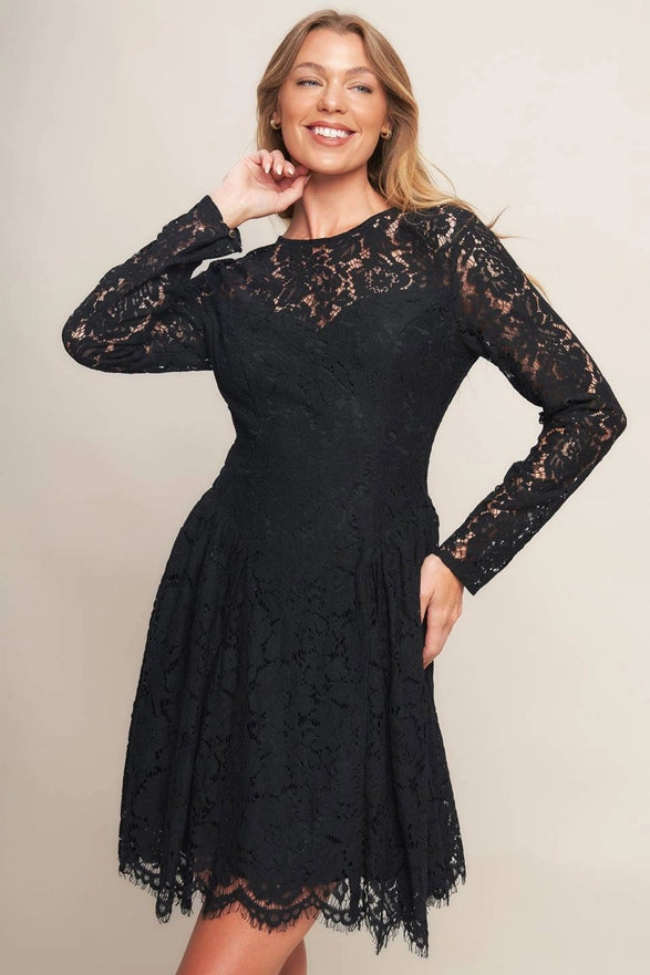 Woman wearing a black lace dress against a plain background