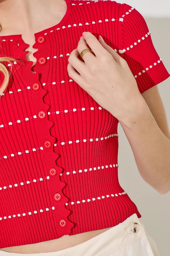 Red ribbed knit top with white buttons and trim on a plain background