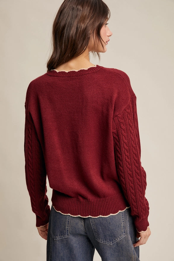 Person wearing a maroon sweater with a neutral background