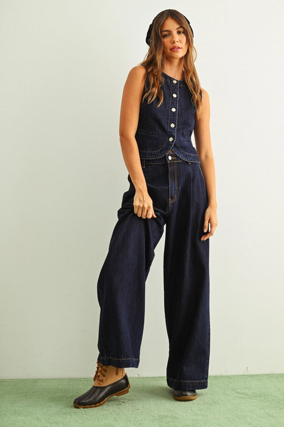 Woman wearing a dark denim jumpsuit on a light green background