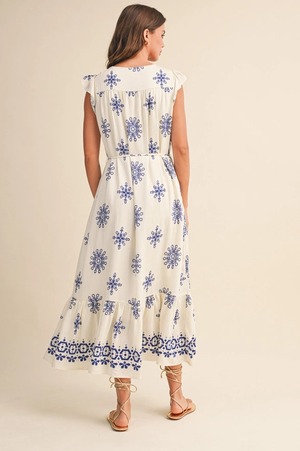 Woman wearing a white dress with blue floral patterns on a beige background