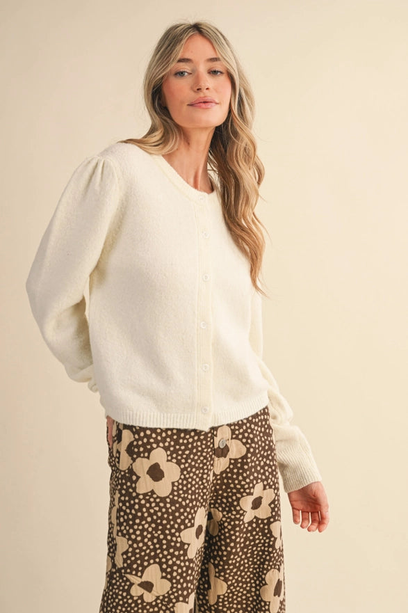 Woman wearing a white sweater and patterned pants on a beige background
