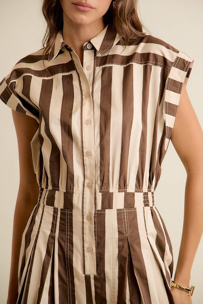 Woman wearing a sleeveless brown and beige striped dress against a neutral background