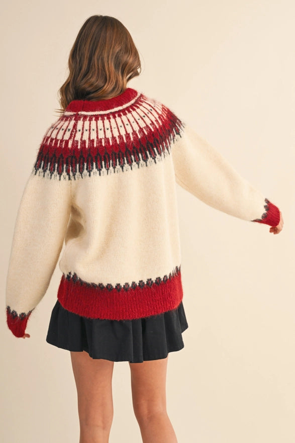 Person wearing a cream sweater with red and black pattern, black skirt, and red gloves on a beige background