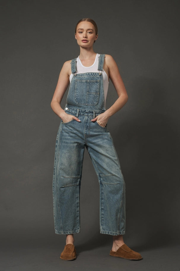 Person wearing blue denim overalls on a dark background