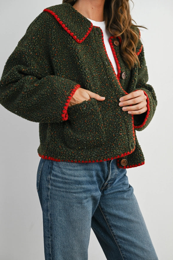 Person wearing a green jacket with red trim and blue jeans on a white background