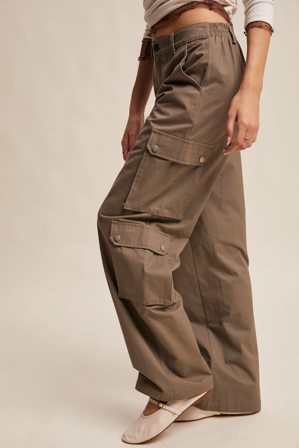 Girl wearing mocha colored cargo pants on plain background.