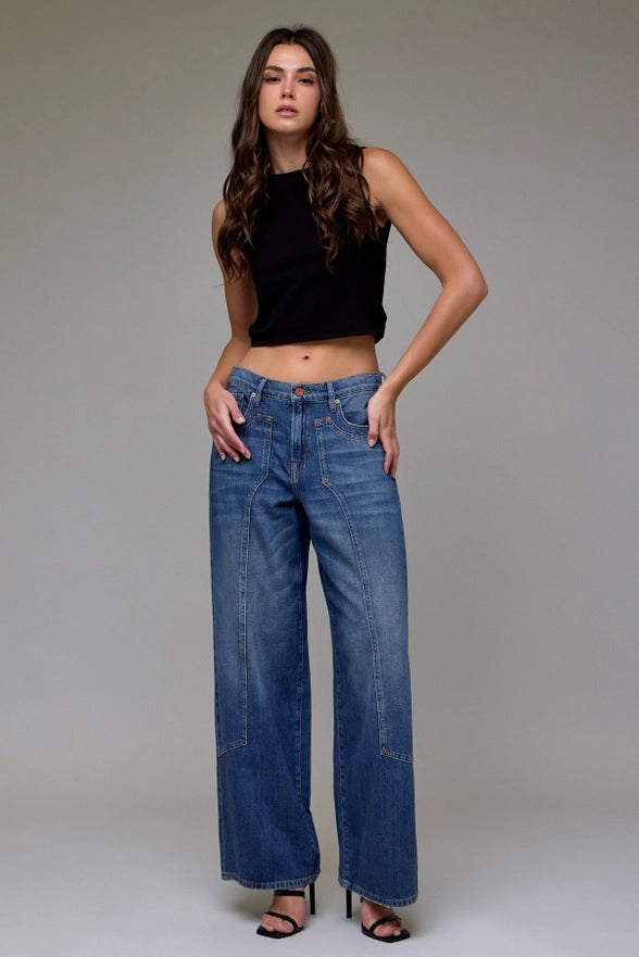 Woman wearing blue jeans and a black top against a plain background