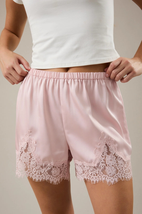 Pink lace shorts worn by a person on a neutral background