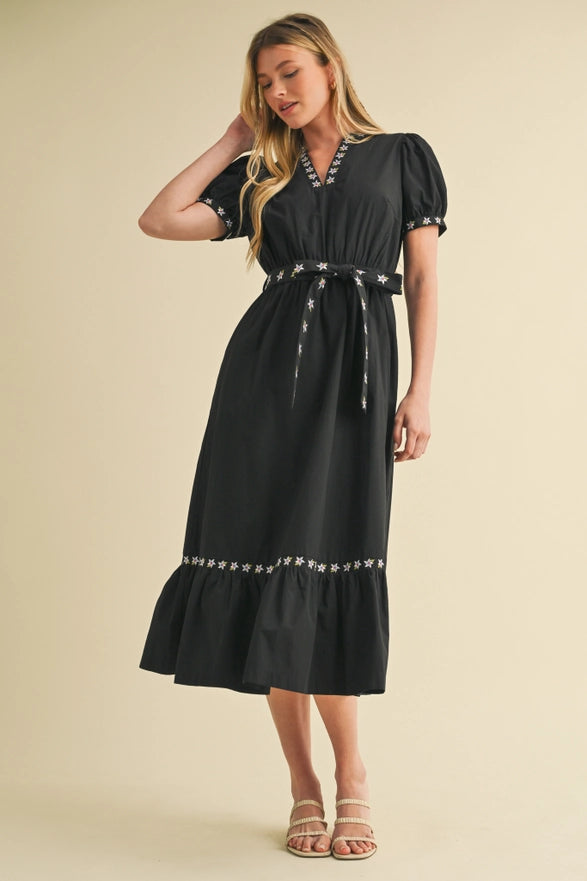 Woman wearing a black dress with decorative trim on a beige background