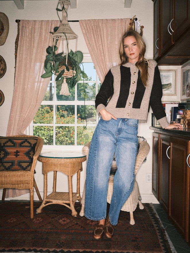 Woman standing in a cozy room with a window and decorative items.