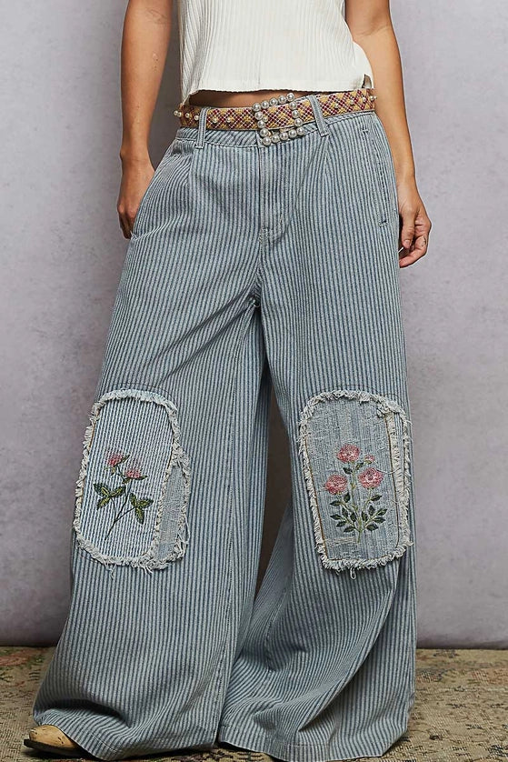 Wide-leg jeans with floral embroidery on a plain background
