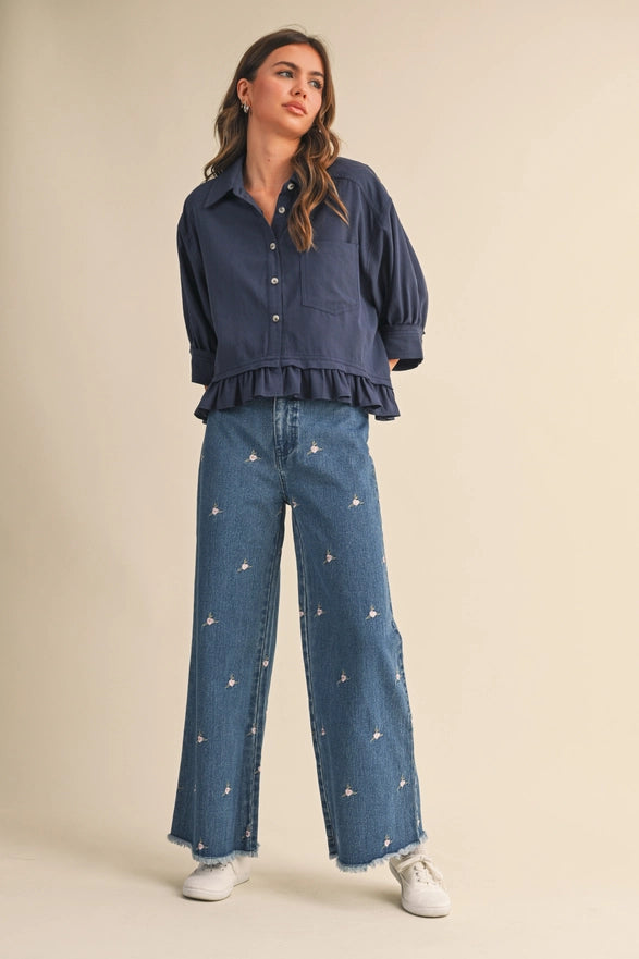 Woman wearing a navy blue shirt and jeans with star patterns on a beige background
