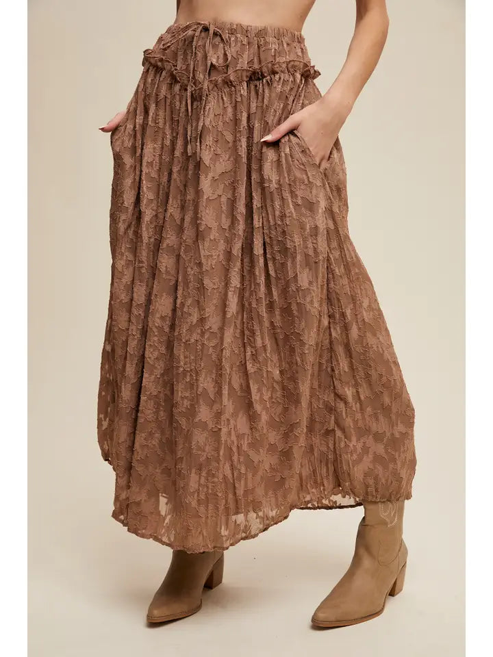 Brown patterned skirt worn by a person on a beige background