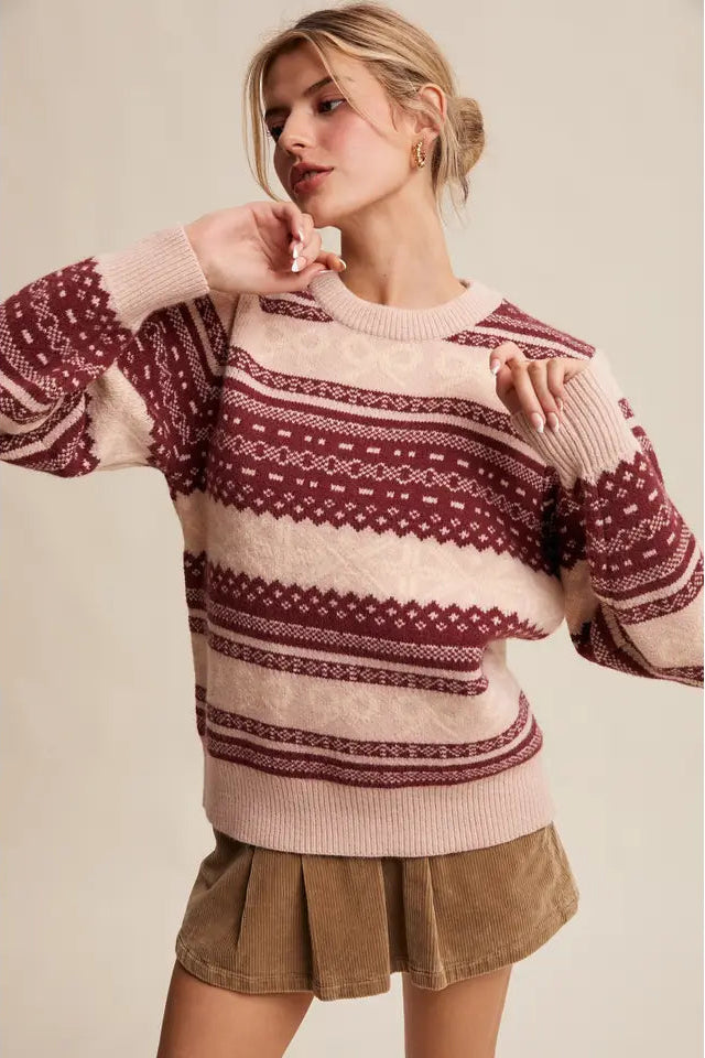 Woman wearing a patterned sweater and skirt against a plain background