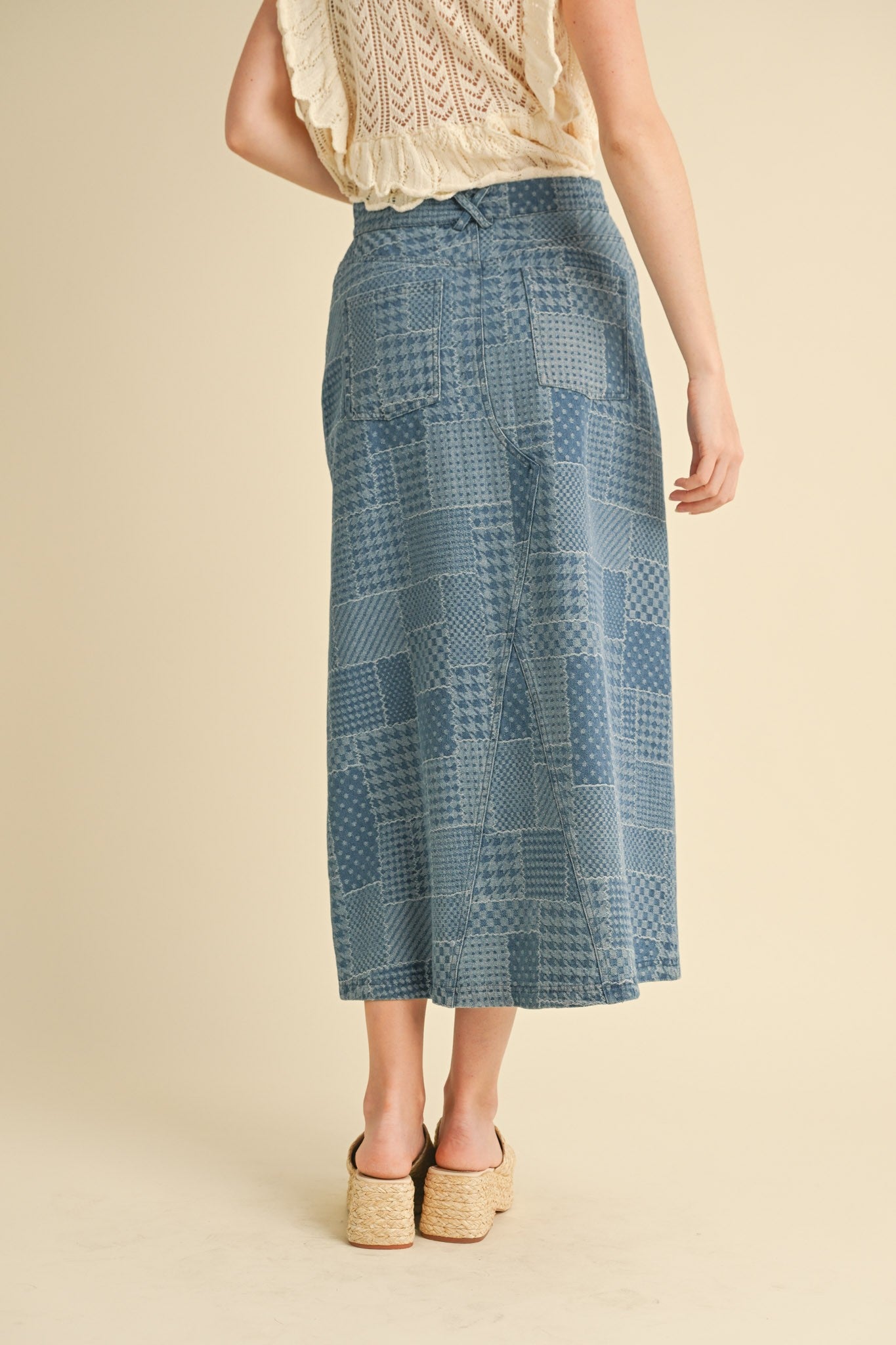 Person wearing a blue patterned skirt on a beige background
