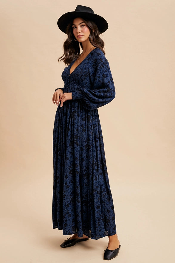 Woman wearing an indigo floral maxi dress on plain background.