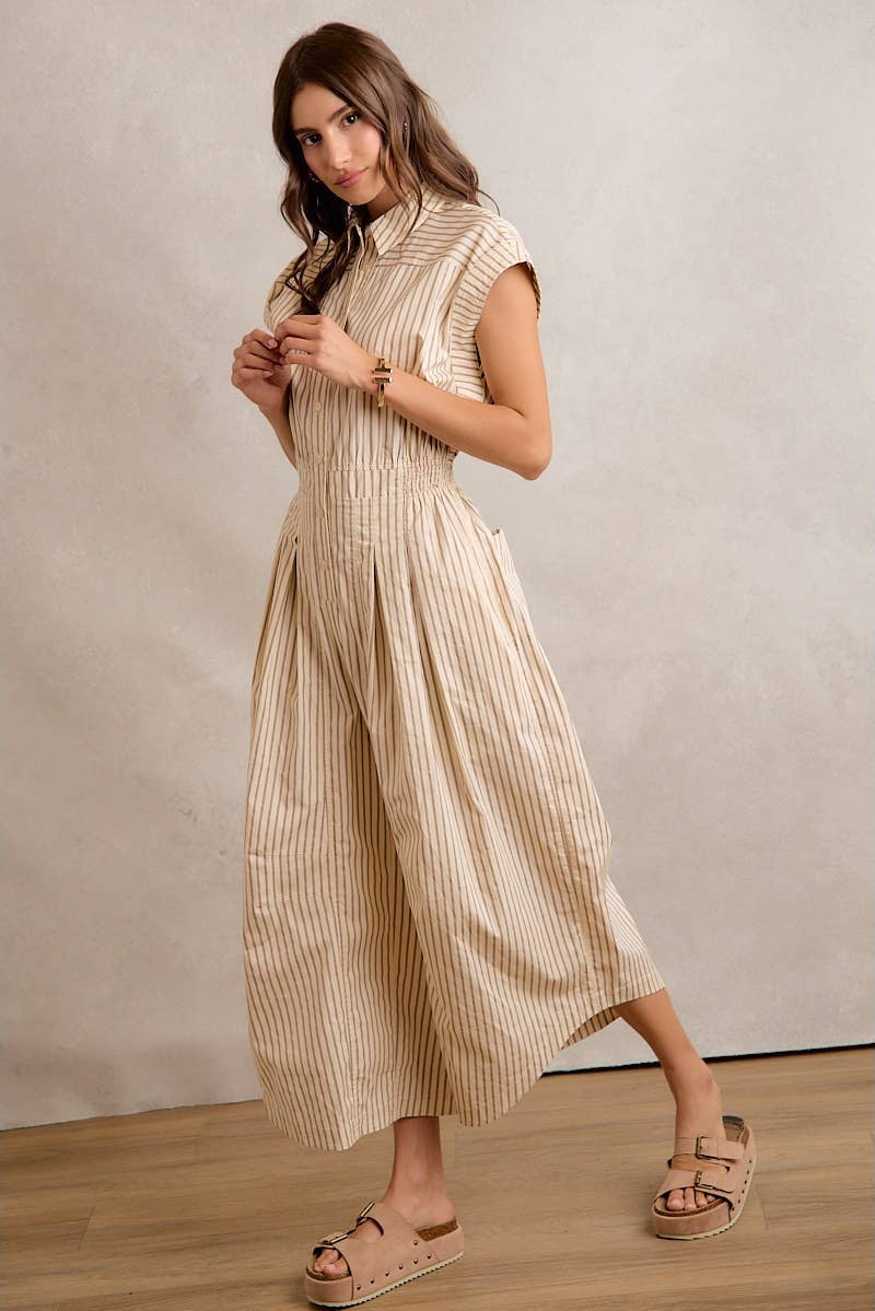 Woman wearing a beige striped dress with wide-leg pants against a plain background