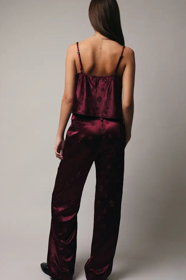 Person wearing a burgundy satin pajama set against a plain background