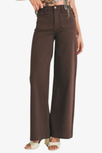Woman wearing a camouflage top and brown high-waisted pants on a white background