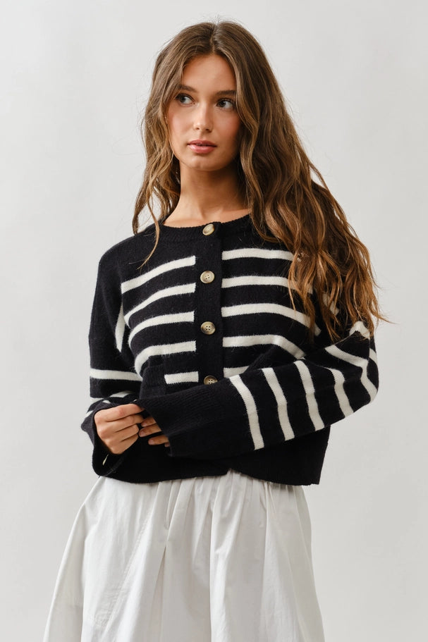 Woman wearing a black and white striped cardigan against a plain background