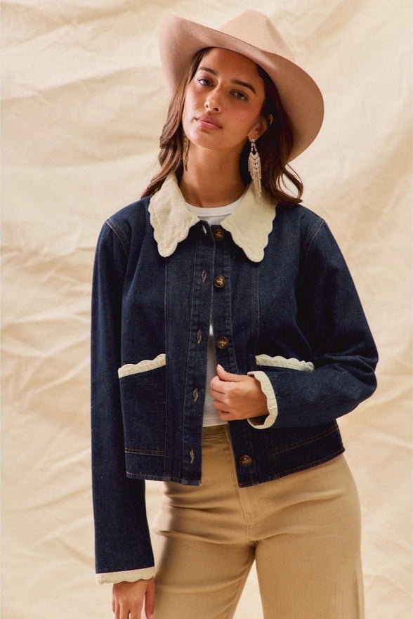 Woman wearing a denim jacket with white trim and a beige hat on a beige background