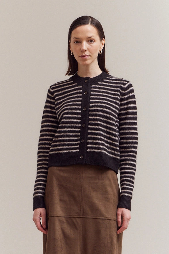 Woman wearing a black and white striped sweater with a plain background