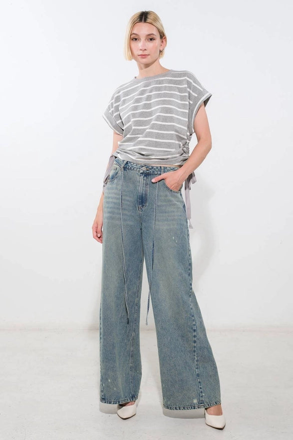 Person wearing a striped shirt and wide-leg jeans on a white background