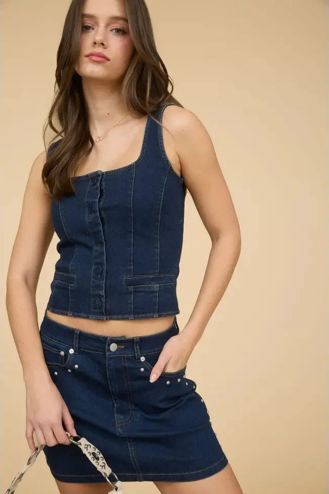 A woman wearing a square neckline sleeveless button-down corset vest with a denim pattern. The vest is made of a blend of cotton, rayon, polyester, and spandex.