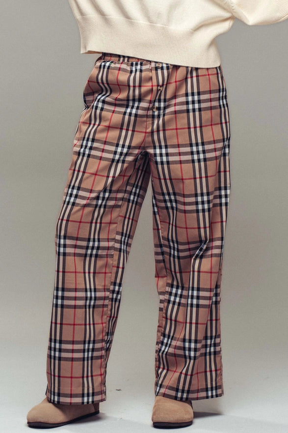 Plaid pants worn with a white top on a plain background