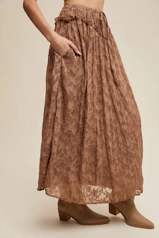 Brown patterned skirt worn by a person on a beige background
