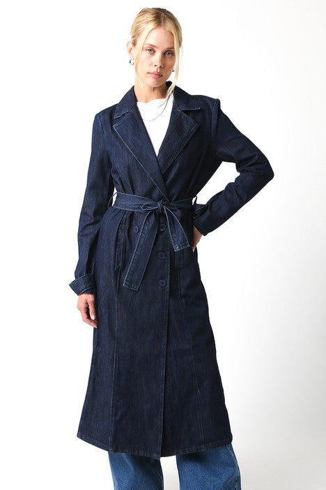 Woman wearing a long navy coat with a white background