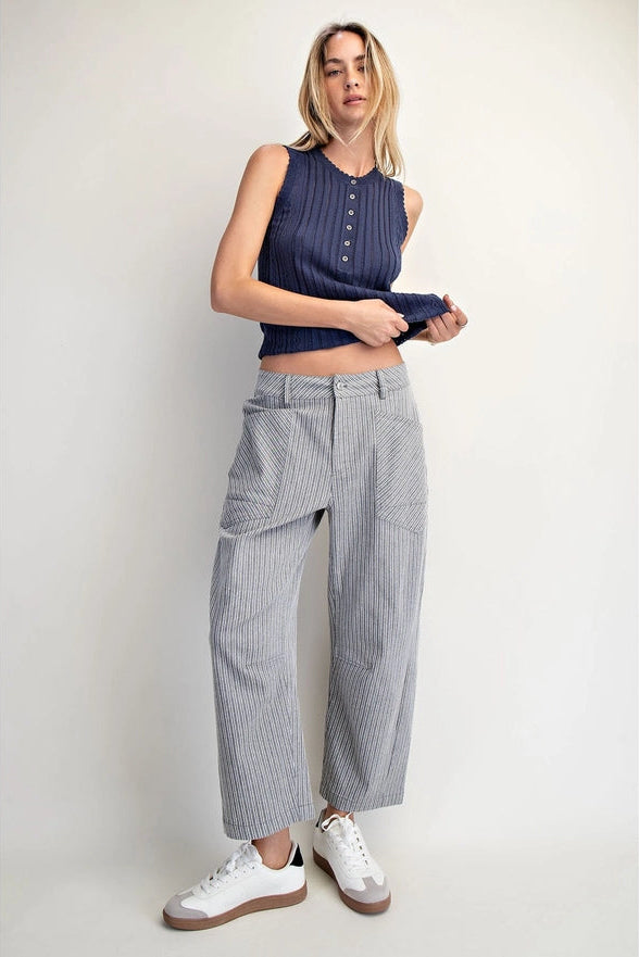 Woman wearing a sleeveless navy top and checkered pants on a plain background