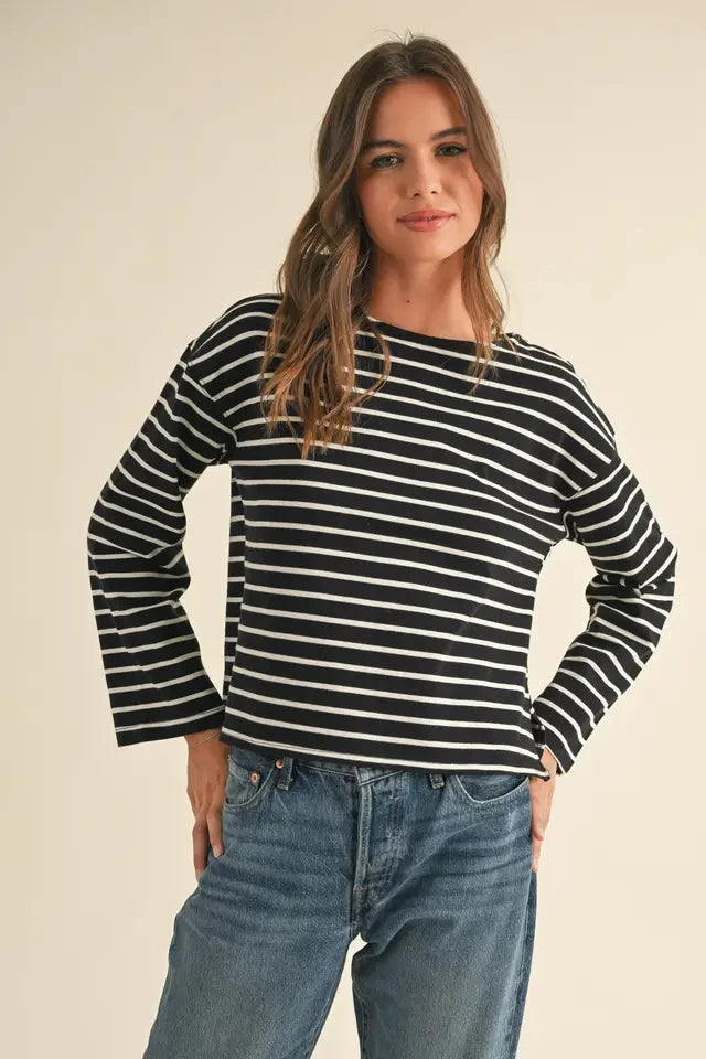 Woman wearing a black and white striped sweater and blue jeans on a beige background