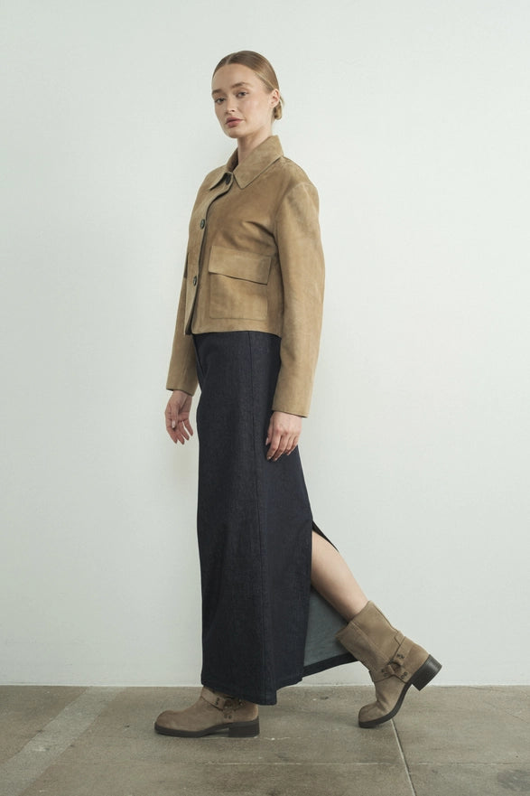 Woman wearing a brown jacket and black skirt against a white background