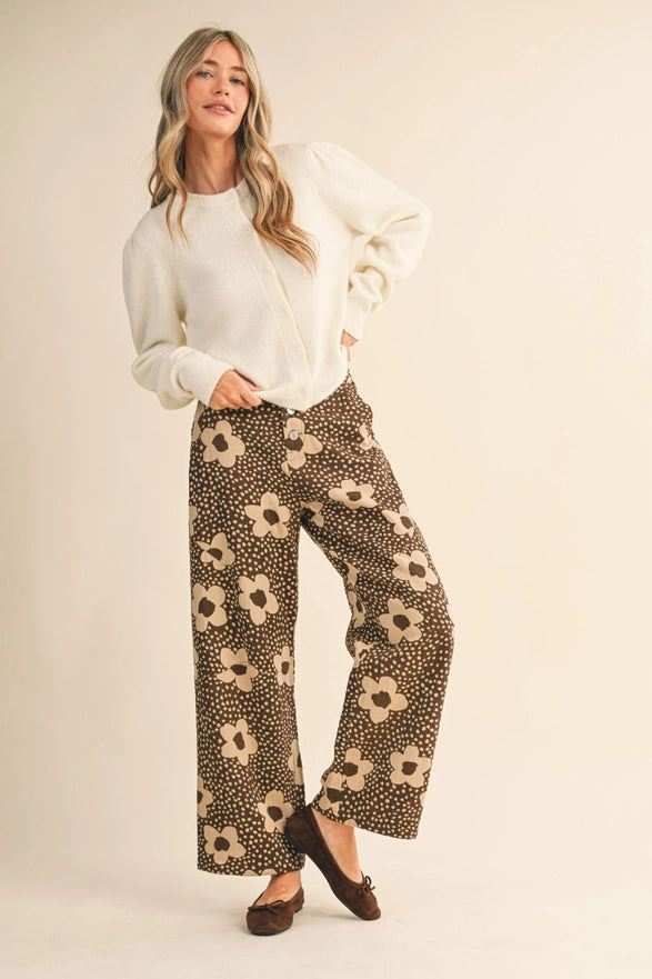 Woman wearing a white top and patterned pants on a beige background